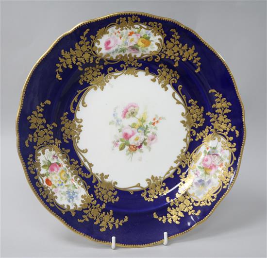 A Coalport cabinet plate, finely painted with floral reserves within gilt foliate cartouches, on a dark blue ground, diam. 26cm